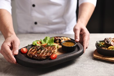 Photo of Professional chef serving dish at table indoors, closeup