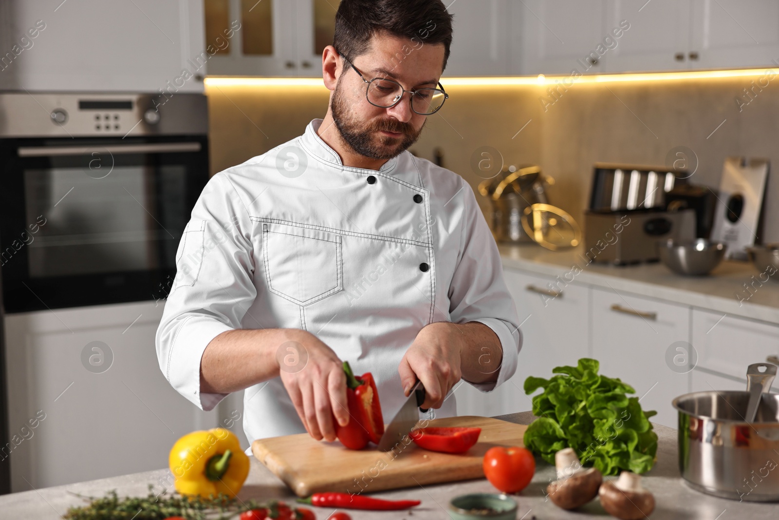 Photo of Professional chef cutting bell pepper at table in kitchen