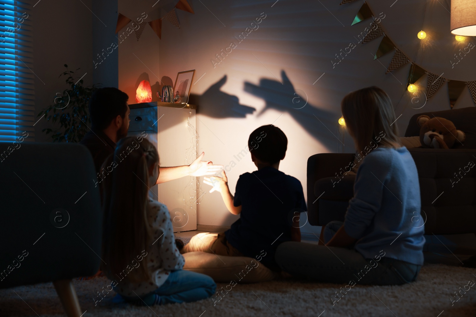 Photo of Shadow play. Father and his son making hand gestures like dogs on wall at home