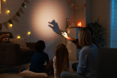 Photo of Man making hand gesture like goose while performing shadow play to his family at home, back view