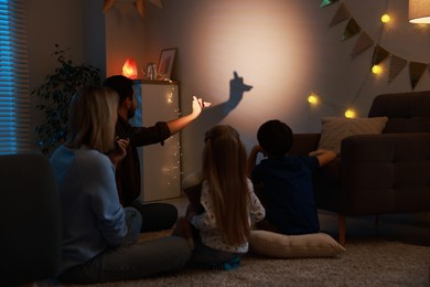 Photo of Man making hand gesture like llama while performing shadow play to his family at home