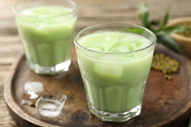 Photo of Fresh mung bean juice with ice on wooden table, closeup