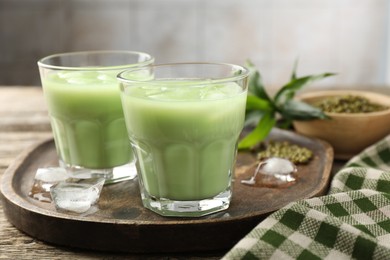 Photo of Fresh mung bean juice with ice in glasses on wooden table, closeup