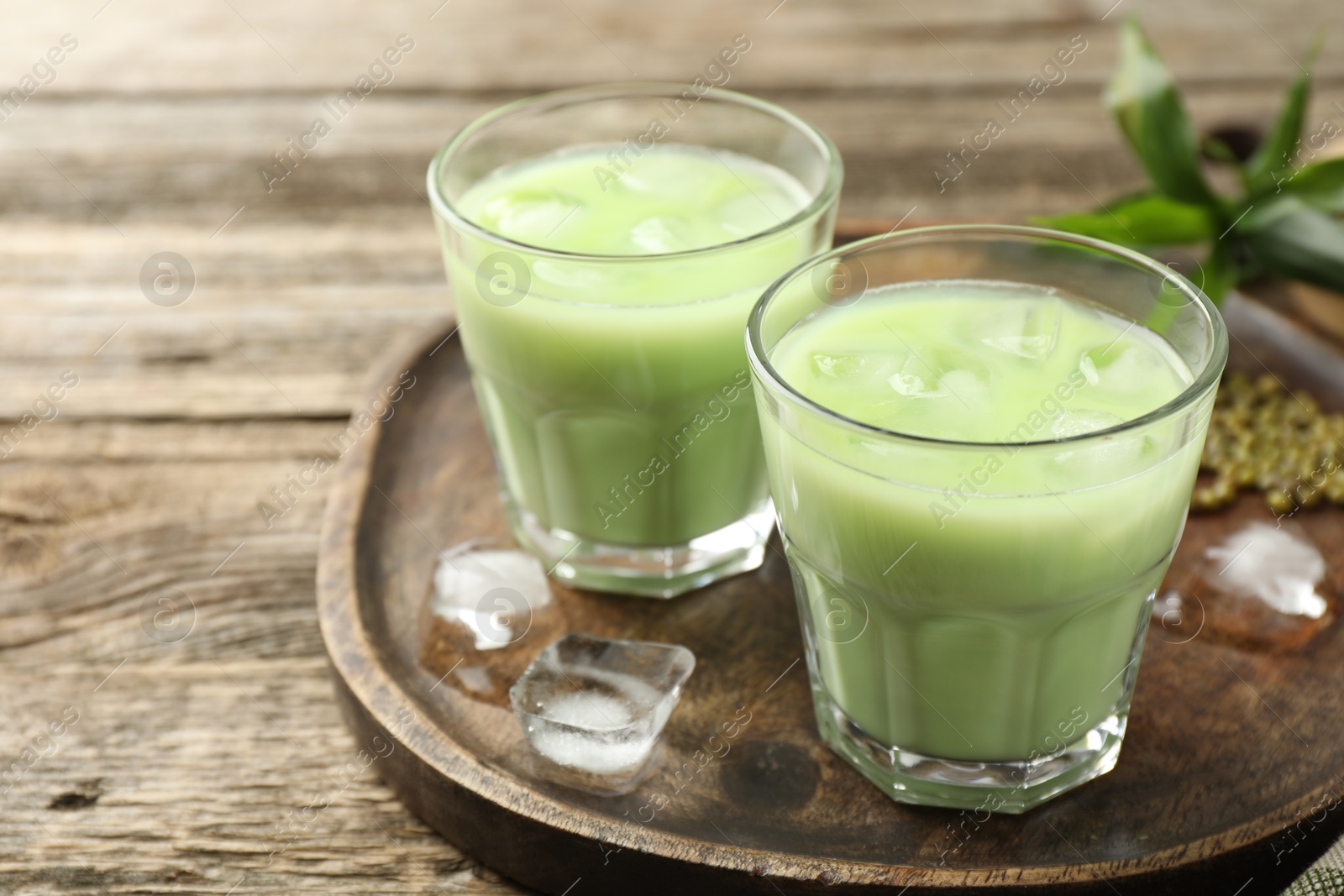 Fresh mung bean juice with ice in glasses on wooden table, closeup. Space for text Photo of Fresh mung bean juice with ice in glasses on wooden table, closeup. Space for text