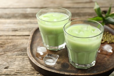 Photo of Fresh mung bean juice with ice in glasses on wooden table, closeup. Space for text