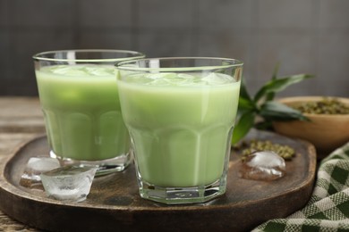 Photo of Fresh mung bean juice with ice in glasses on wooden table, closeup