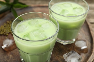 Photo of Fresh mung bean juice with ice in glasses on wooden table, closeup
