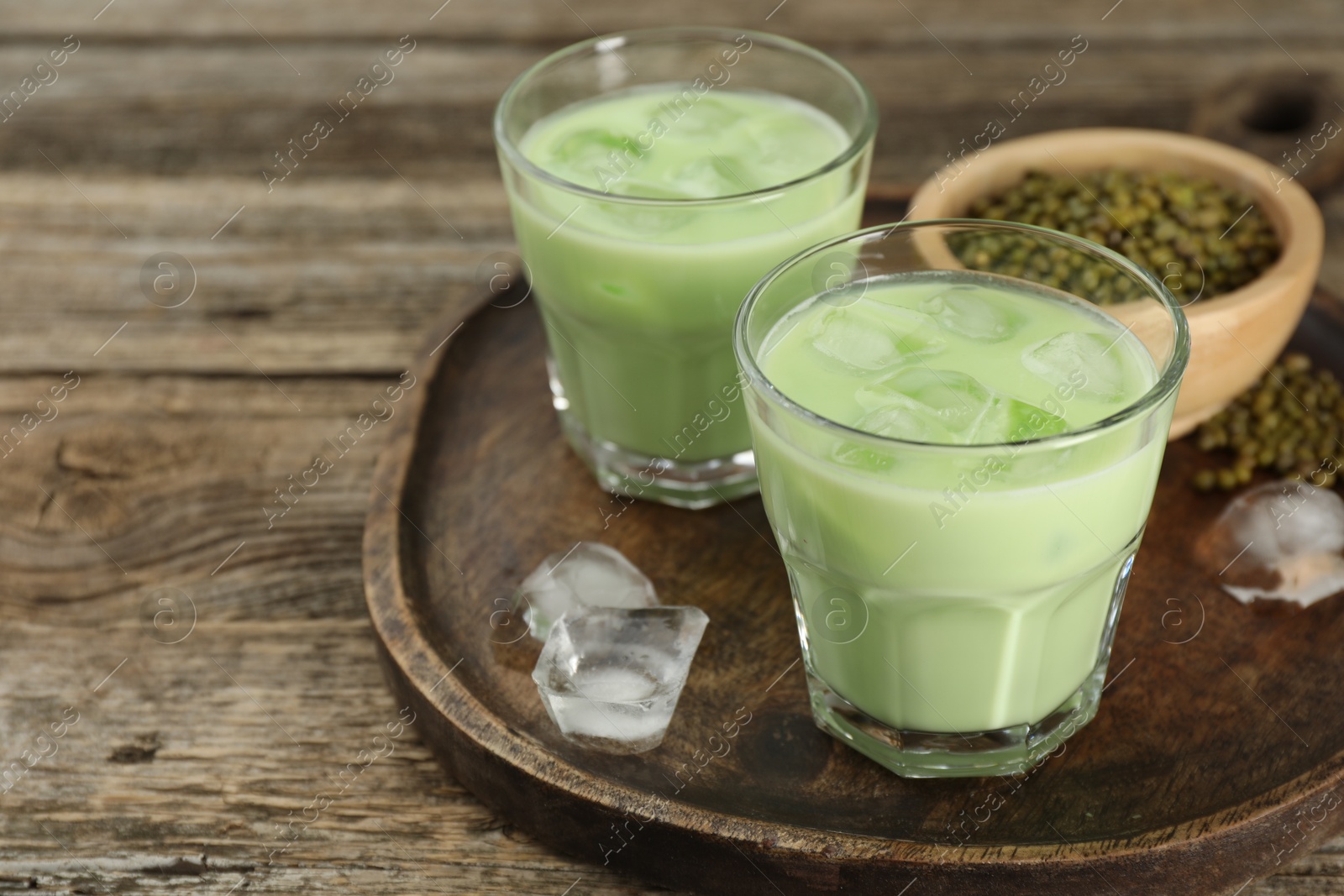 Fresh mung bean juice with ice in glasses and seeds on wooden table, closeup. Space for text Photo of Fresh mung bean juice with ice in glasses and seeds on wooden table, closeup. Space for text