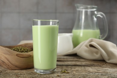 Photo of Fresh mung bean juice in glass and seeds on wooden table, closeup