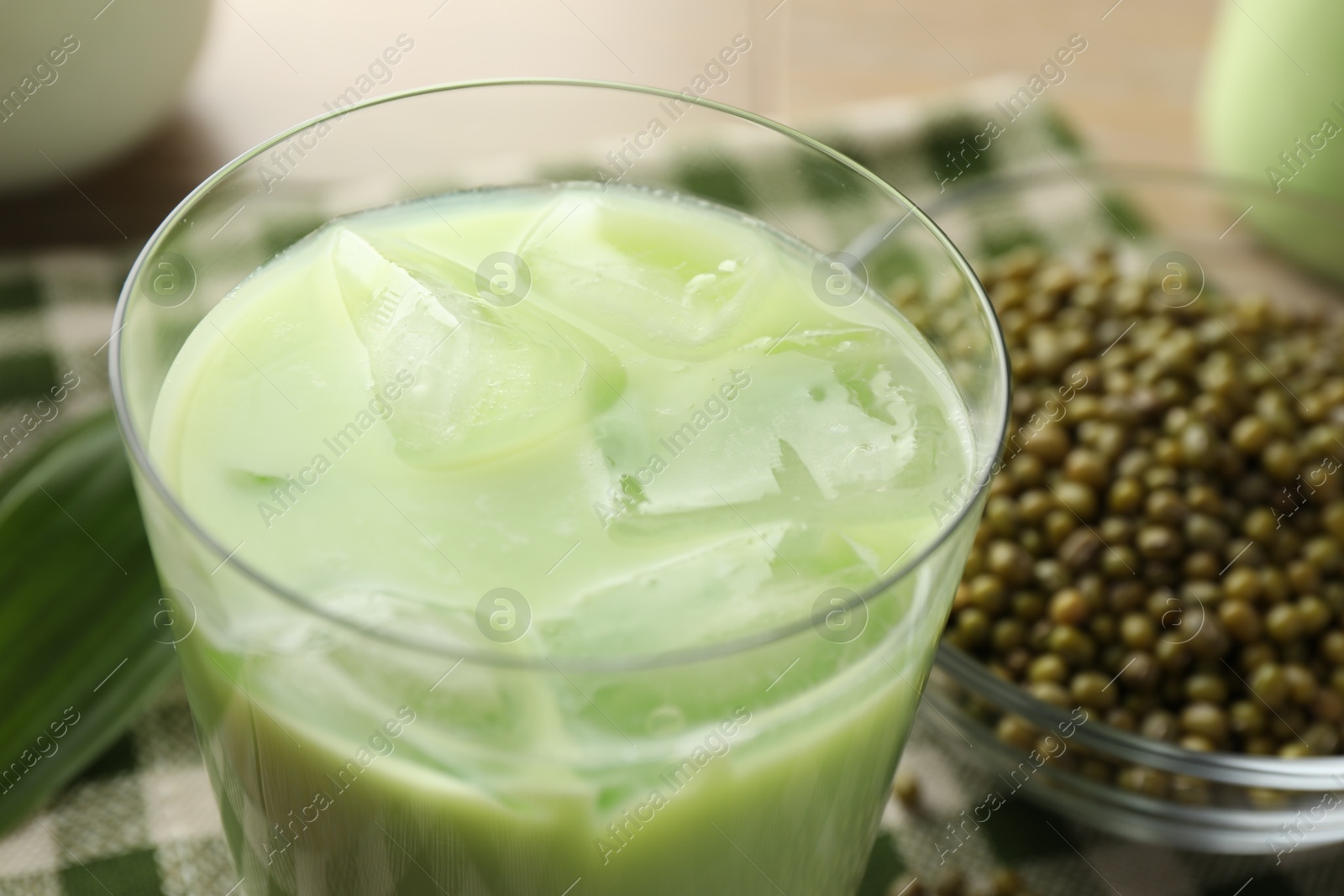 Fresh mung bean juice with ice in glass and seeds on table, closeup Photo of Fresh mung bean juice with ice in glass and seeds on table, closeup