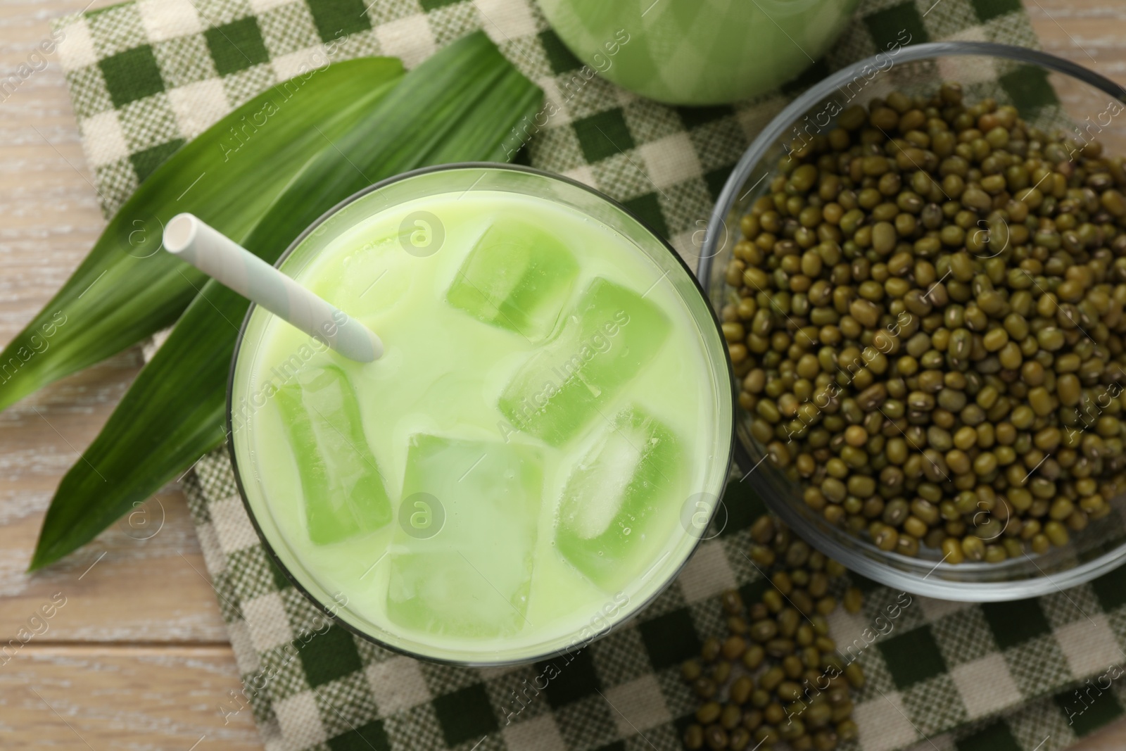 Fresh mung bean juice with ice in glass, leaves and seeds on wooden table, flat lay Photo of Fresh mung bean juice with ice in glass, leaves and seeds on wooden table, flat lay