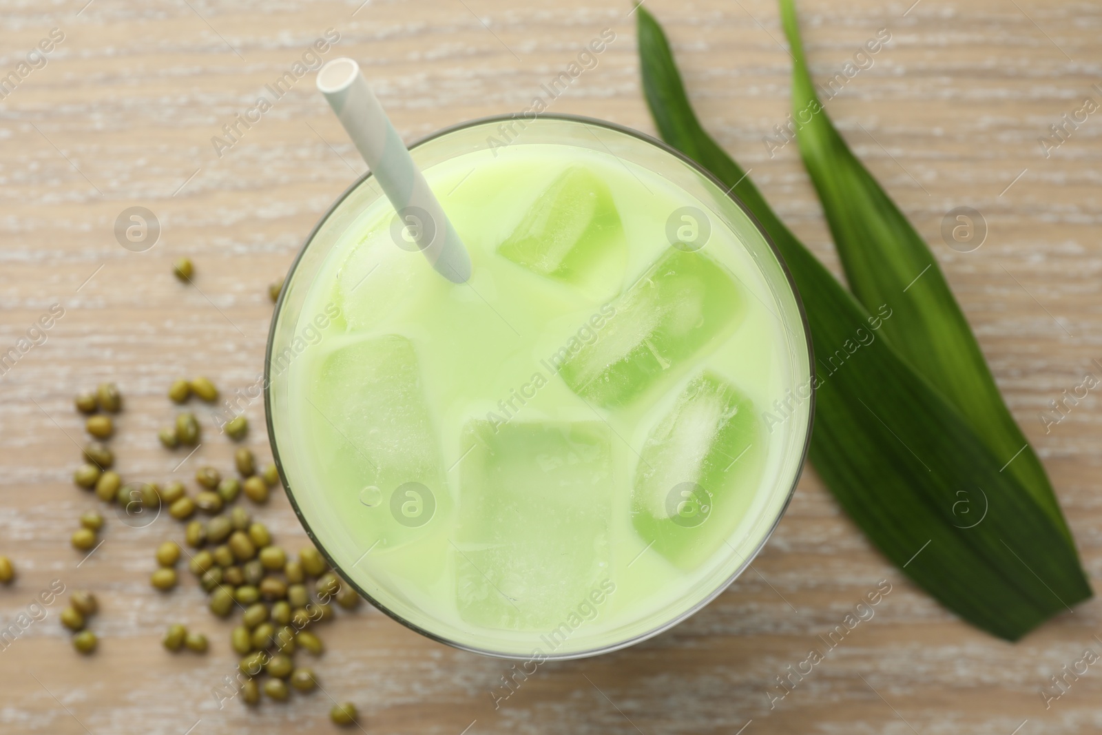 Fresh mung bean juice with ice in glass, leaves and seeds on wooden table, flat lay Photo of Fresh mung bean juice with ice in glass, leaves and seeds on wooden table, flat lay