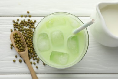 Photo of Fresh mung bean juice with ice in glass, milk and seeds on white wooden table, flat lay