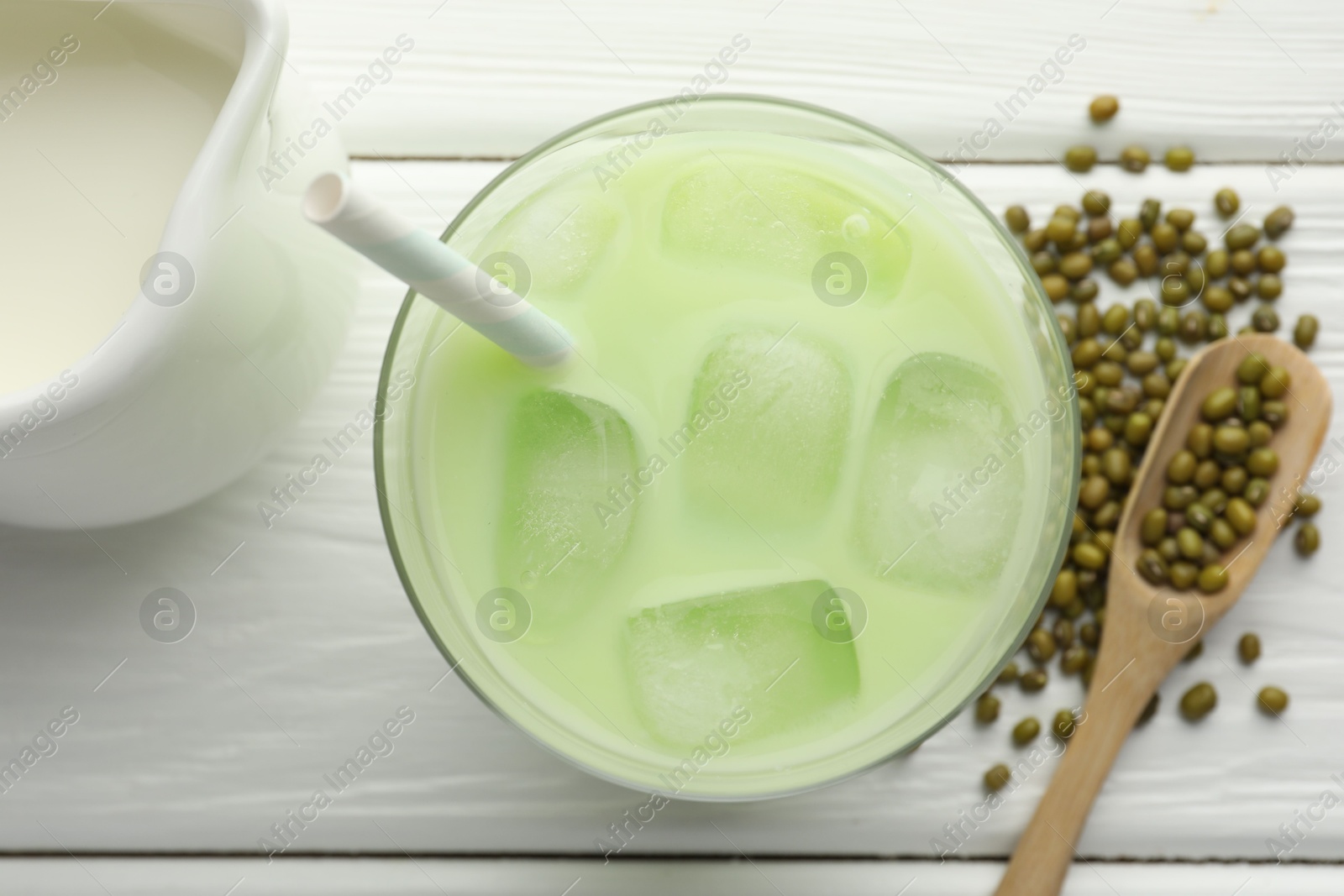 Fresh mung bean juice with ice in glass, milk and seeds on white wooden table, flat lay Photo of Fresh mung bean juice with ice in glass, milk and seeds on white wooden table, flat lay