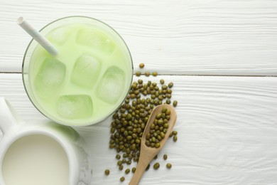 Photo of Fresh mung bean juice with ice in glass, milk and seeds on white wooden table, flat lay. Space for text