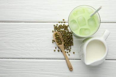 Photo of Fresh mung bean juice with ice in glass, milk and seeds on white wooden table, flat lay. Space for text