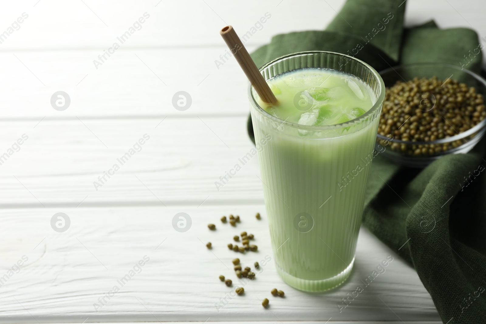 Fresh mung bean juice with ice in glass and seeds on white wooden table, closeup. Space for text Photo of Fresh mung bean juice with ice in glass and seeds on white wooden table, closeup. Space for text