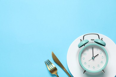 Photo of Time for meal. Alarm clock, plate and cutlery on light blue background, flat lay. Space for text