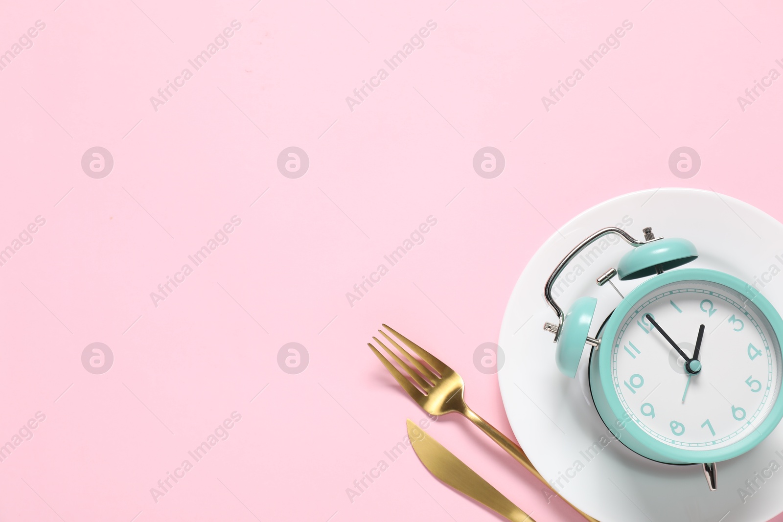 Photo of Time for meal. Alarm clock, plate and cutlery on pink background, flat lay. Space for text