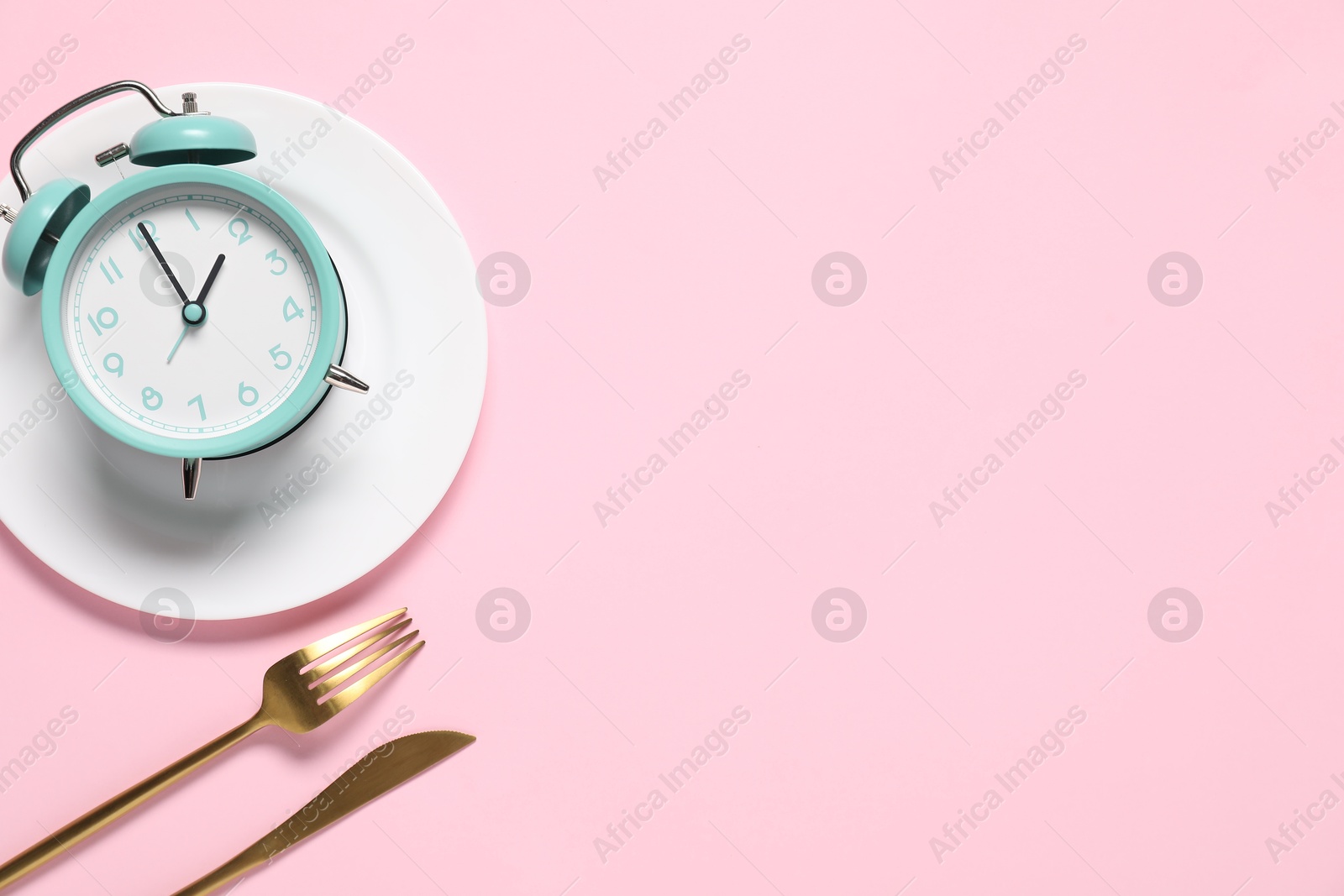 Photo of Time for meal. Alarm clock, plate and cutlery on pink background, flat lay. Space for text