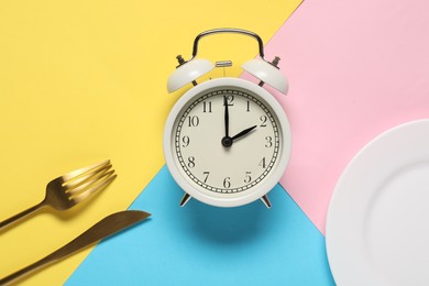 Photo of Time for meal. Alarm clock, plate and cutlery on color background, flat lay