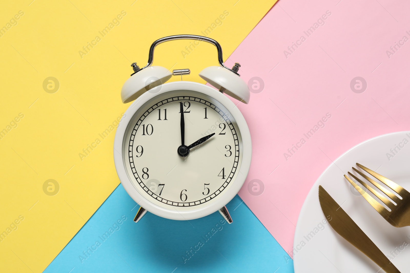 Photo of Time for meal. Alarm clock, plate and cutlery on color background, flat lay