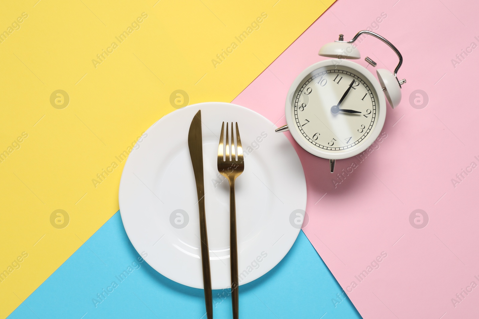 Photo of Time for meal. Alarm clock, plate and cutlery on color background, flat lay