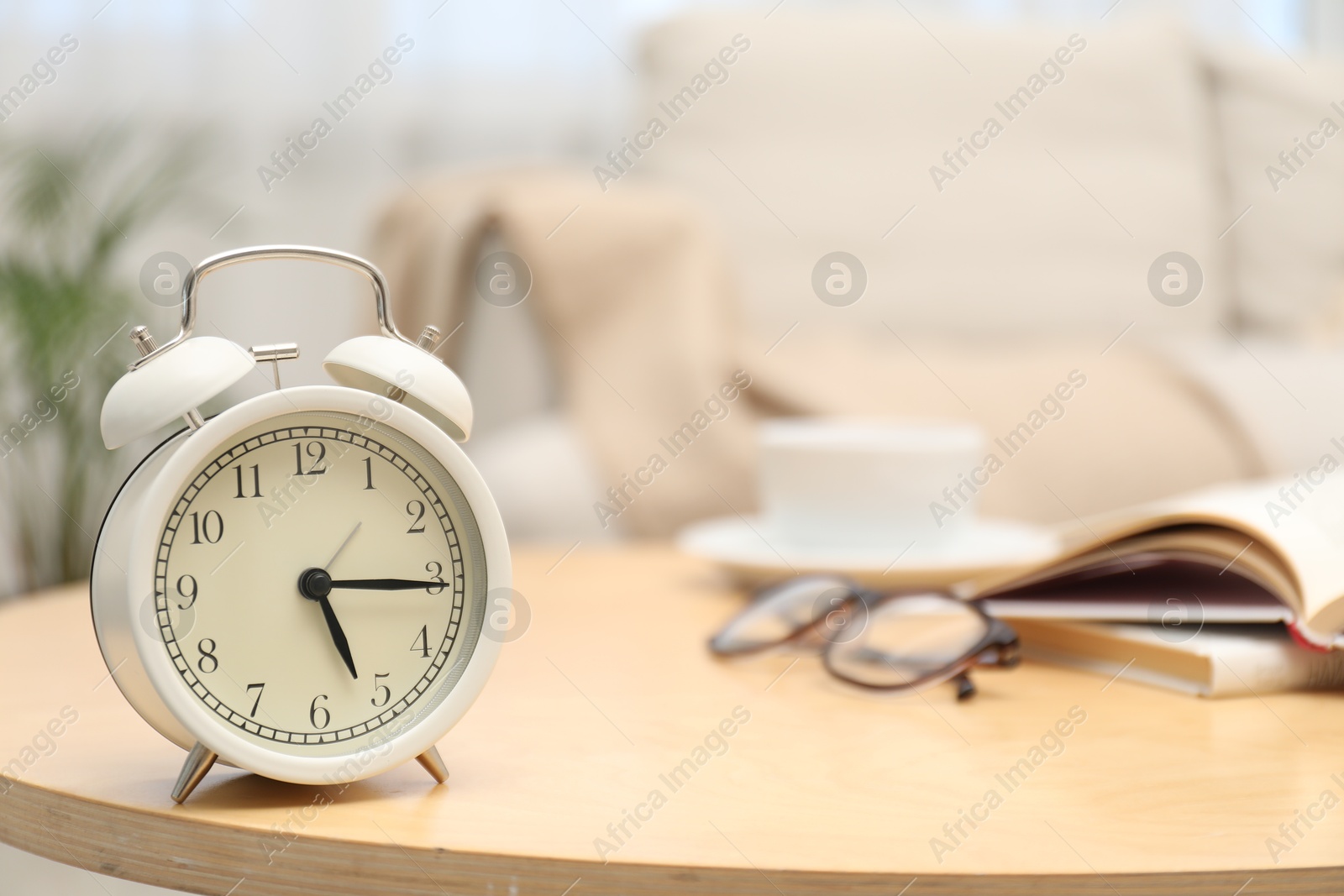 Photo of Time for knowledge. Alarm clock, glasses and books on wooden table indoors, closeup