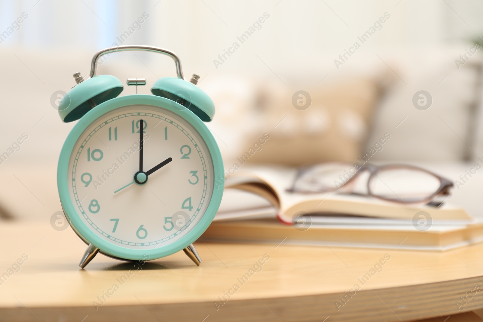 Photo of Time for knowledge. Alarm clock, glasses and books on wooden table indoors, closeup