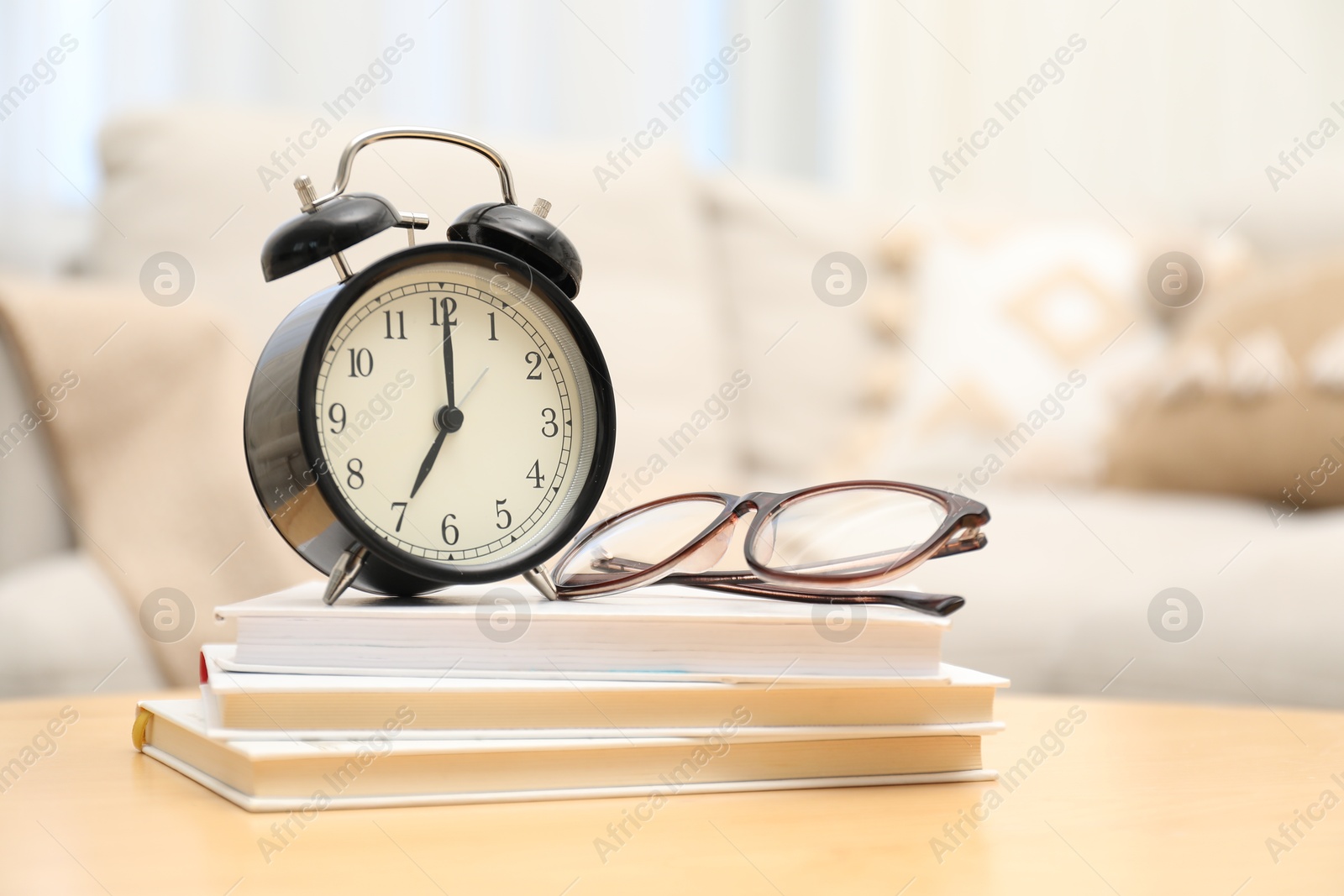 Photo of Time for knowledge. Alarm clock, glasses and books on wooden table indoors, space for text