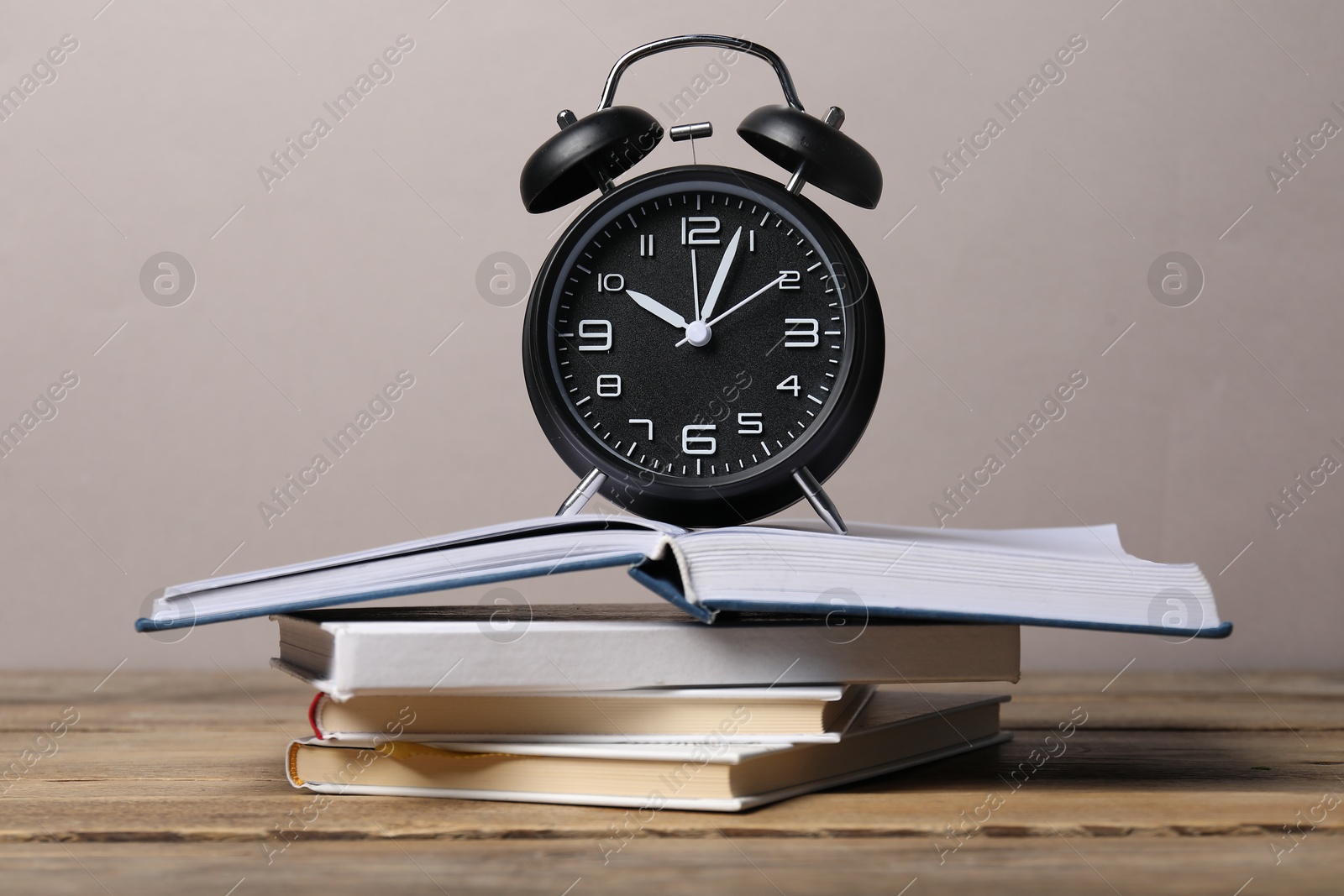 Photo of Time for knowledge. Alarm clock and books on wooden table