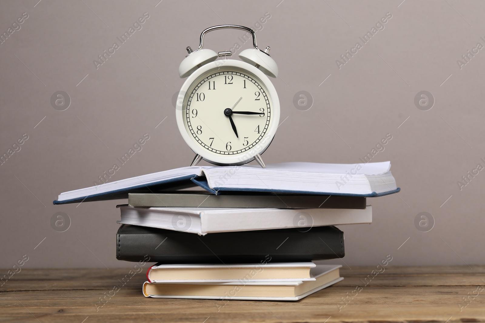 Photo of Time for knowledge. Alarm clock and books on wooden table