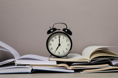 Photo of Time for knowledge. Alarm clock and open books on white wooden table