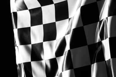 Photo of One racing checkered flag on black background, closeup