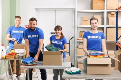 Photo of Group of volunteers packing donation goods at tables indoors