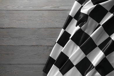 Photo of Checkered flag on grey wooden table, top view. Space for text