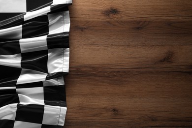 Photo of Checkered flag on wooden table, top view. Space for text