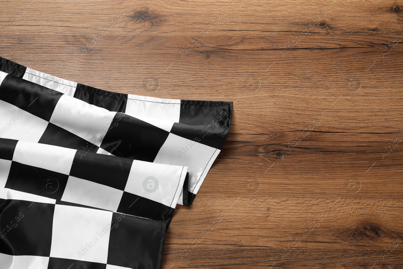 Photo of Checkered flag on wooden table, top view. Space for text