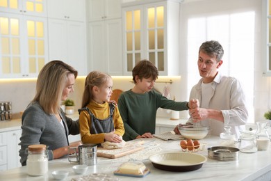 Photo of Happy family making dough at white marble table in kitchen