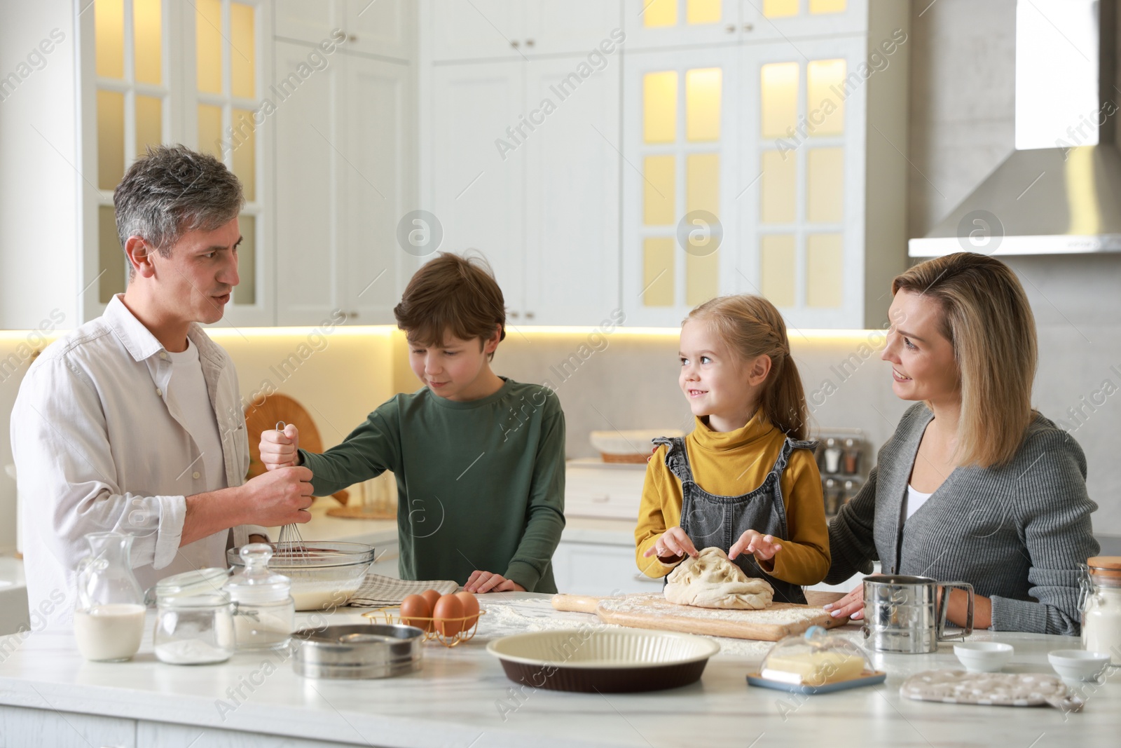 Photo of Happy family making dough at white marble table in kitchen