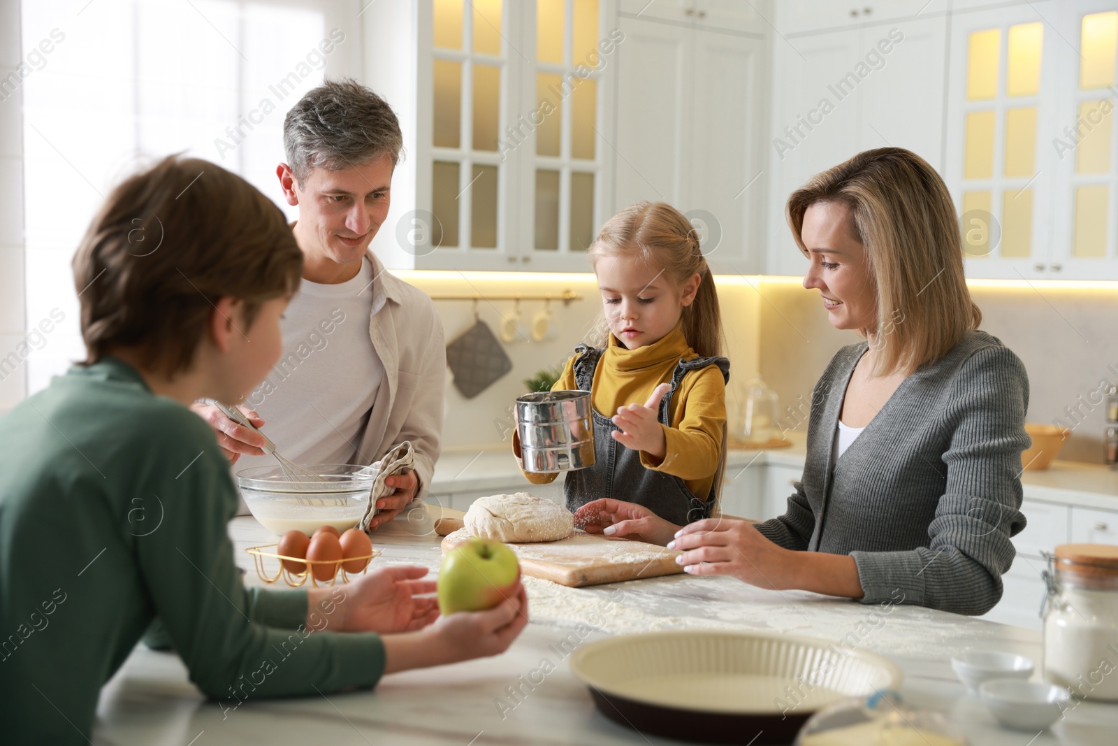 Photo of Happy family making dough at table in kitchen