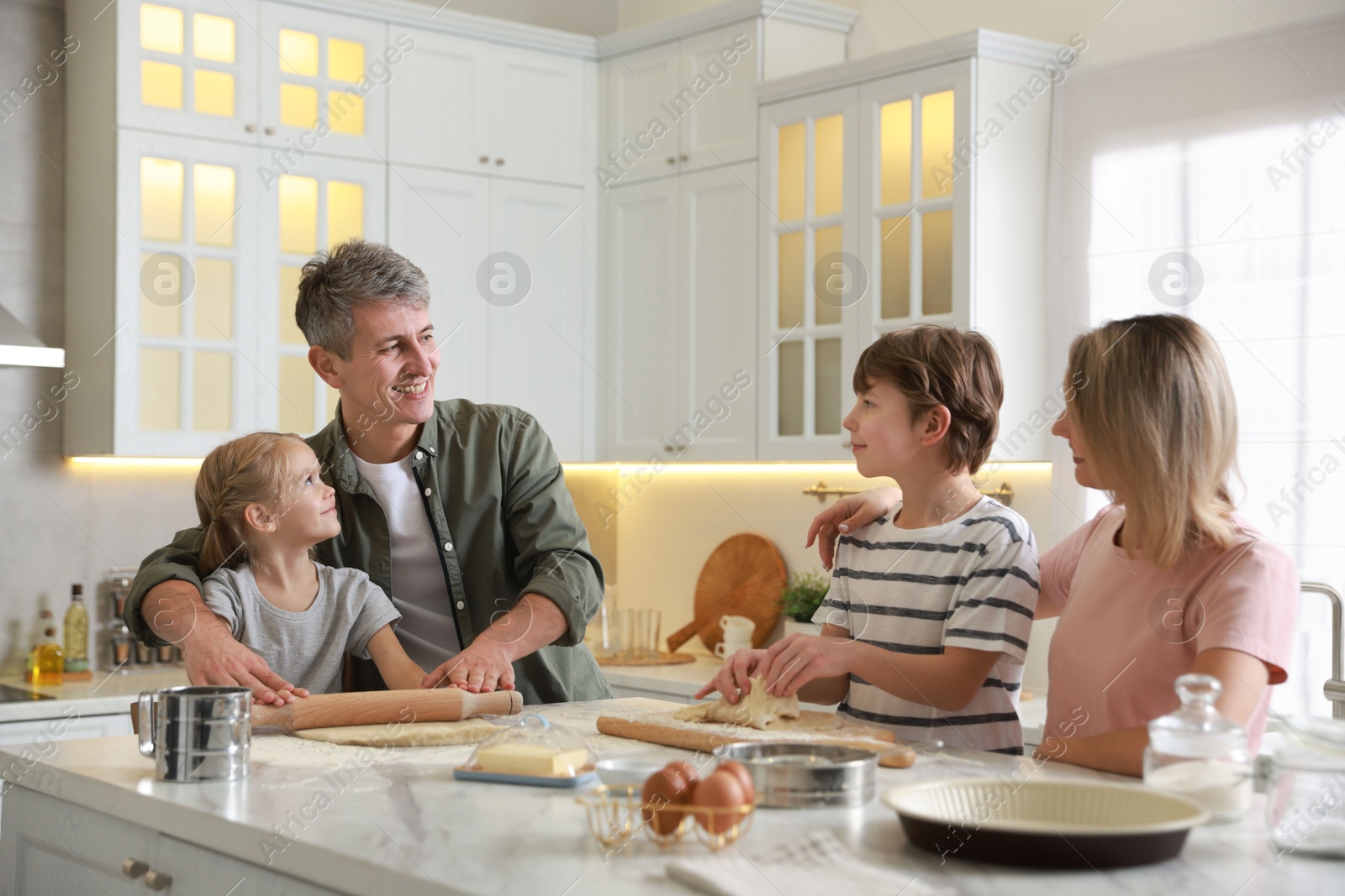 Photo of Happy family making dough at white marble table in kitchen