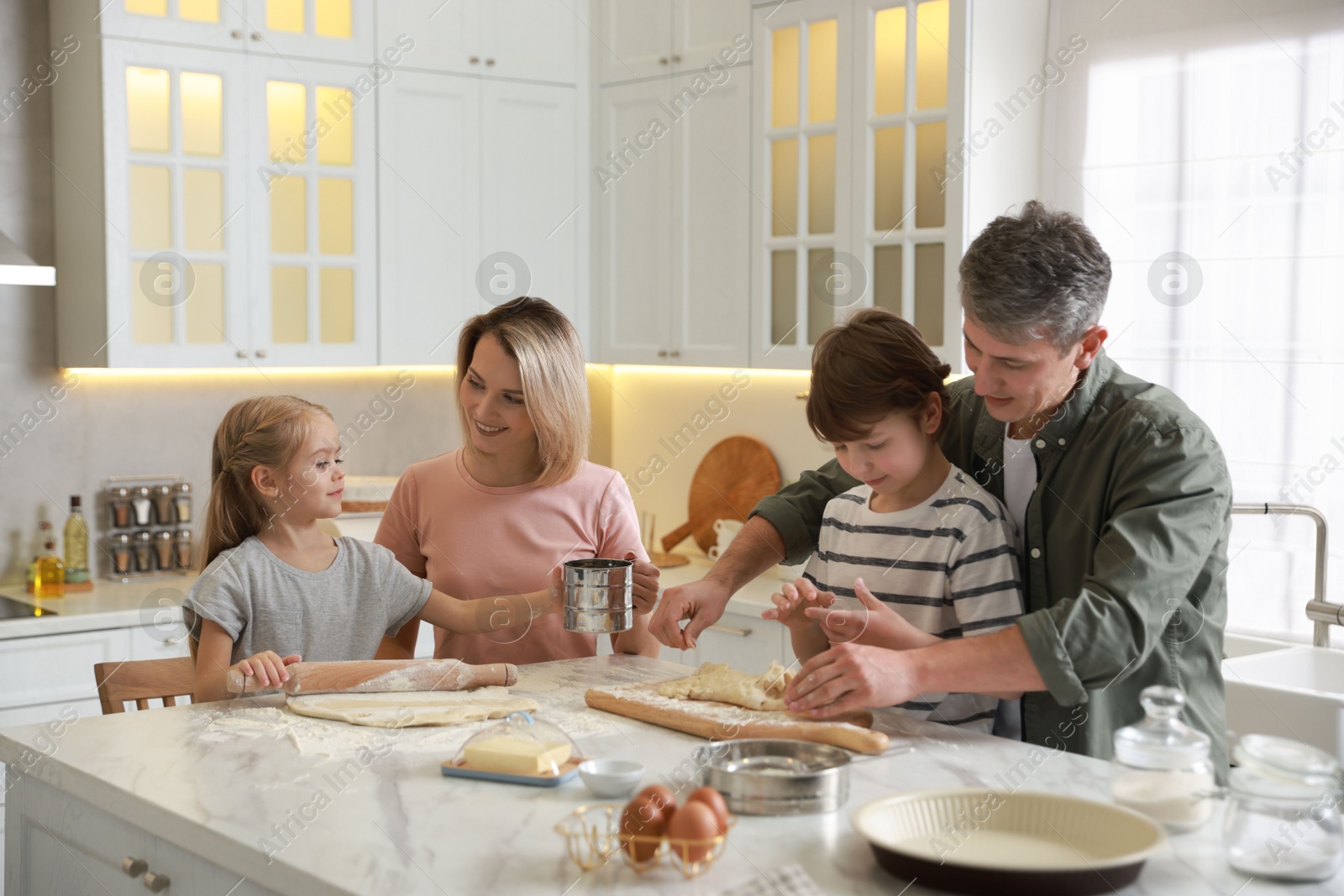 Photo of Happy family making dough at white marble table in kitchen