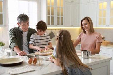 Photo of Happy family making dough at white marble table in kitchen