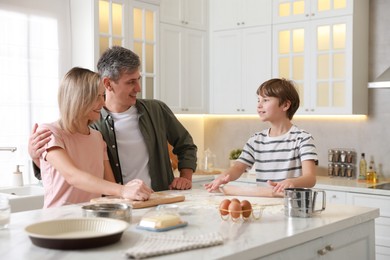 Photo of Happy family kneading dough at white marble table in kitchen