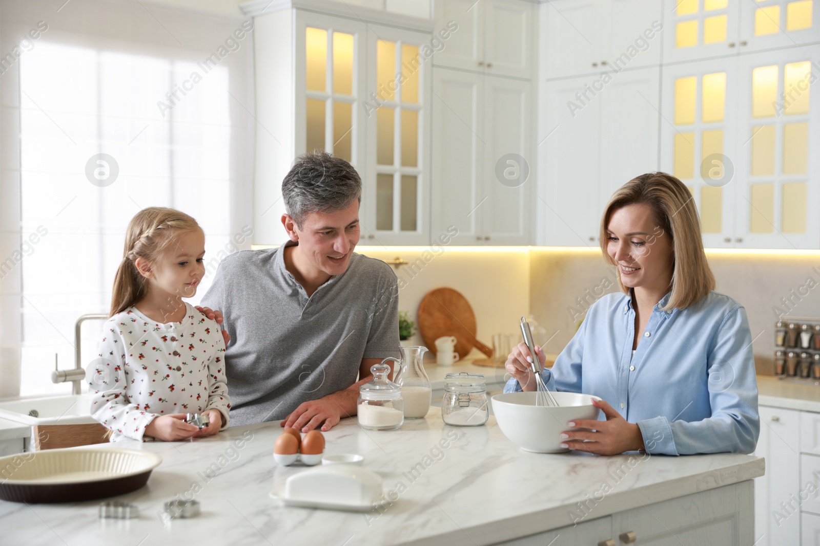 Photo of Happy family making dough at white marble table in kitchen