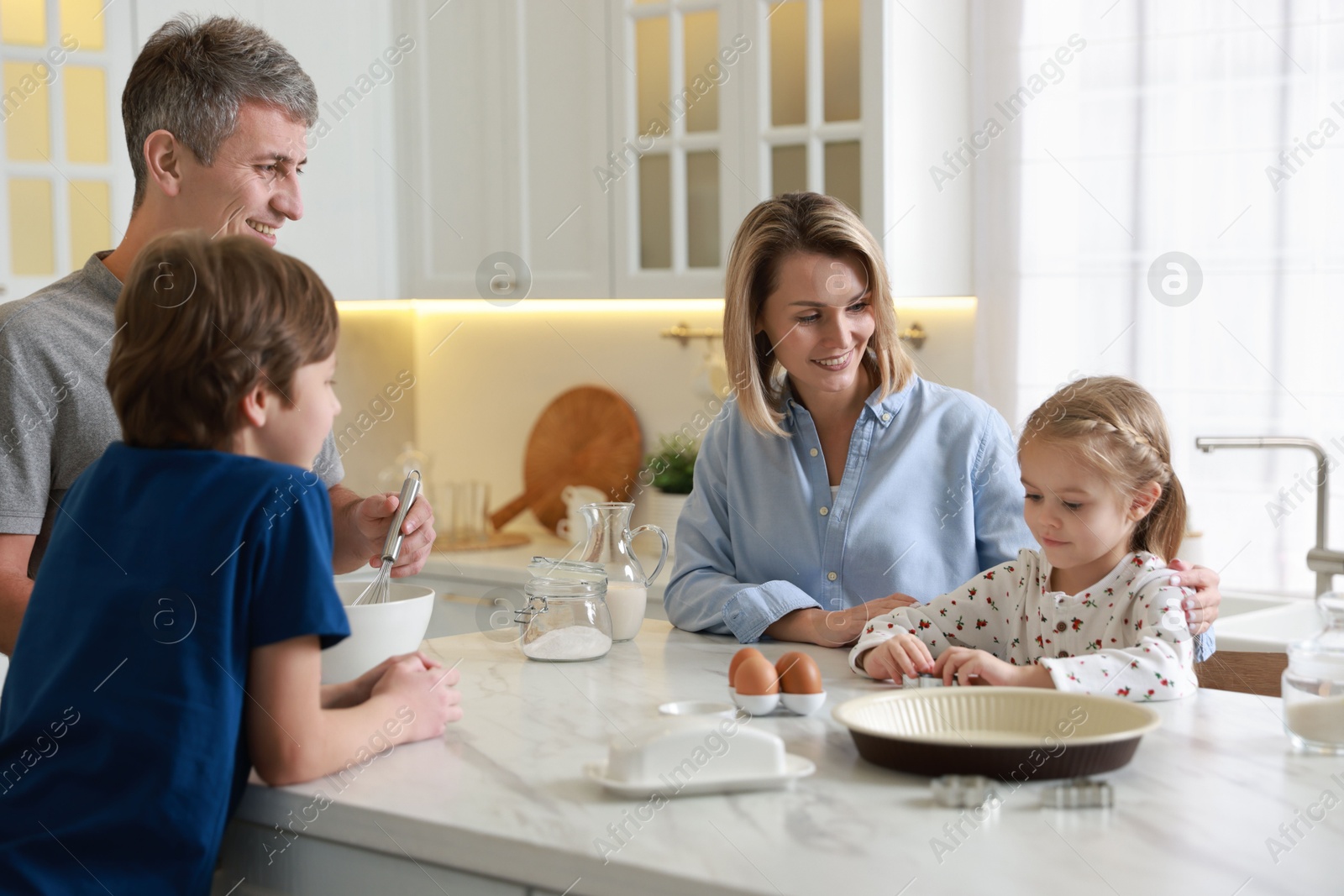 Photo of Happy family making dough at white marble table in kitchen