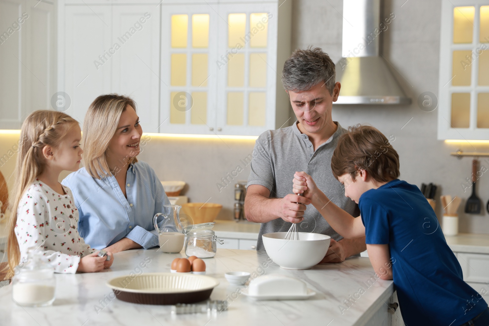 Photo of Happy family making dough at white marble table in kitchen