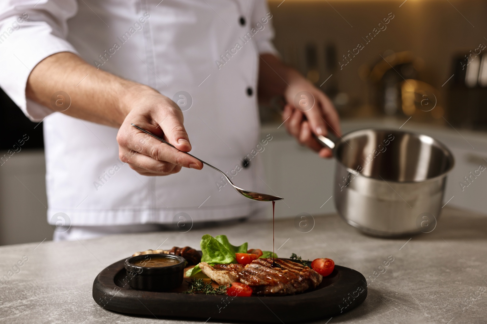 Photo of Professional chef adding sauce to delicious dish at table indoors, closeup