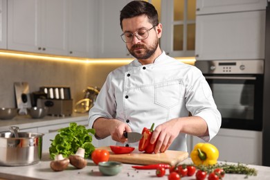 Photo of Professional chef cutting bell pepper at table in kitchen